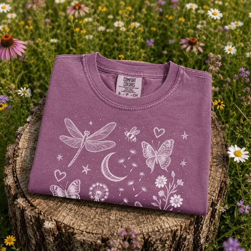 Comfort Colors garment-dyed t-shirt featuring a vintage botanical design with dragonflies, butterflies, bees, wildflowers, dandelions, floating seeds, hearts, stars, and a crescent moon.