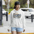 Woman wearing a hoodie with a lighthouse design and 'East Coast' text on a street.