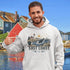 Person wearing East Coast Canada hoodie featuring lighthouse, ocean, and marine wildlife design in a coastal village setting