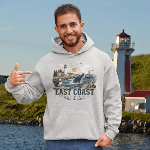 Man wearing a hoodie with 'East Coast' design in front of a lighthouse.