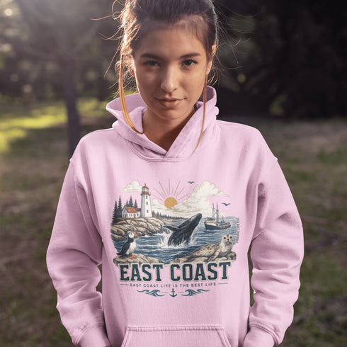 Person wearing a pink hoodie with a scenic design and 'East Coast' text, standing outdoors.
