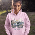 Person wearing a pink hoodie with a scenic design and 'East Coast' text, standing outdoors.