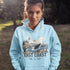 Person wearing a light blue hoodie with a coastal design and 'East Coast' text outdoors.