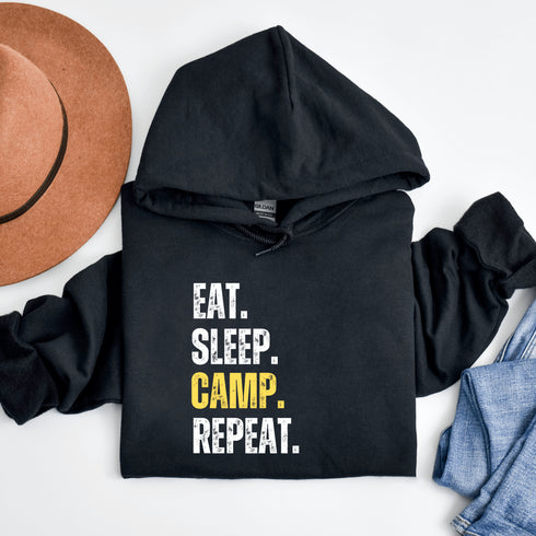 Introducing the ultimate camper's companion: the "Eat. Sleep. Camp. Repeat." Hoodie! This isn't just any ordinary piece of clothing. It's your best friend in the wilderness, your cozy confidante under the stars, and quite possibly the most honest representation of your weekend plans.