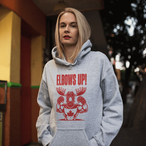 Get ready to hit the ice (or the couch) in style with our "Elbows Up!" hoodie! Featuring a tough-as-nails moose rocking a Canada hockey shirt and helmet while flexing its muscles