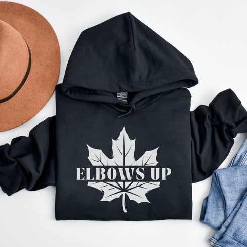 Featuring a bold maple leaf and the iconic "Elbows Up" phrase, this hoodie lets everyone know you’re not afraid to play hard—on the ice, in life