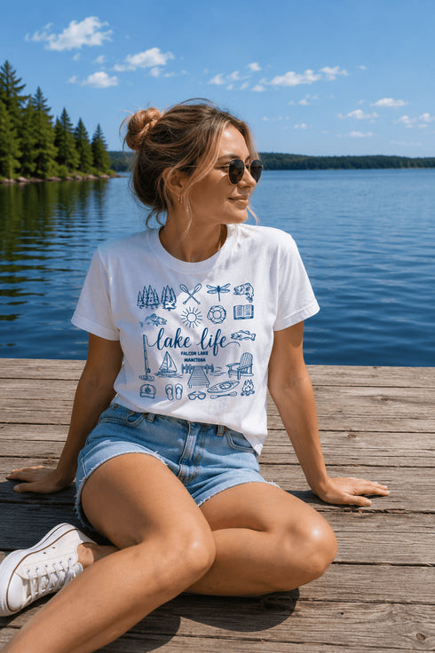 Woman sitting on a dock by a lake wearing a 'Lake Life' t-shirt.