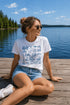 Woman sitting on a dock by a lake wearing a 'Lake Life' t-shirt.