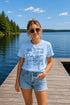 Woman wearing a 'Lake Life' t-shirt standing on a dock by a lake.