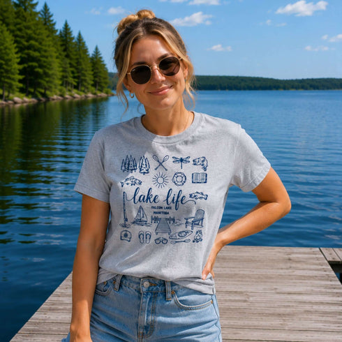 Woman wearing a 'Lake Life' t-shirt by a lake with trees in the background