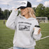 woman wearing grey hoodie with “Fear The Goalie” soccer goalkeeper design featuring diving goalie making a save