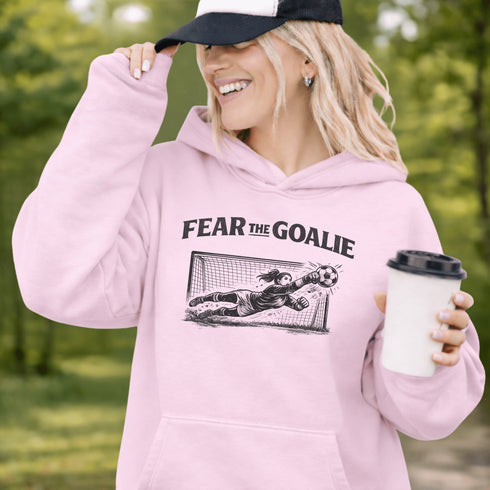 woman wearing grey hoodie with “Fear The Goalie” soccer goalkeeper design featuring diving goalie making a save