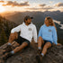 Vintage outdoor graphic hoodie featuring a small left chest design and a large mountain landscape graphic on the back, available in multiple colors and shown in various lifestyle and product mockups.