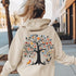 This hoodie features a delightful folk art design of vibrant birds perched in a tree adorned with colorful leaves and blooming flowers, creating a scene that radiates joy and creativity.