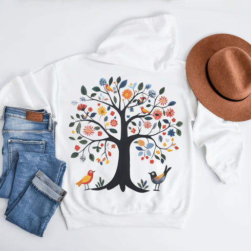 This hoodie features a delightful folk art design of vibrant birds perched in a tree adorned with colorful leaves and blooming flowers, creating a scene that radiates joy and creativity.