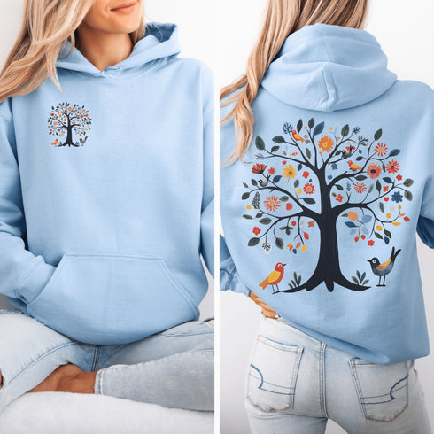 This hoodie features a delightful folk art design of vibrant birds perched in a tree adorned with colorful leaves and blooming flowers, creating a scene that radiates joy and creativity.