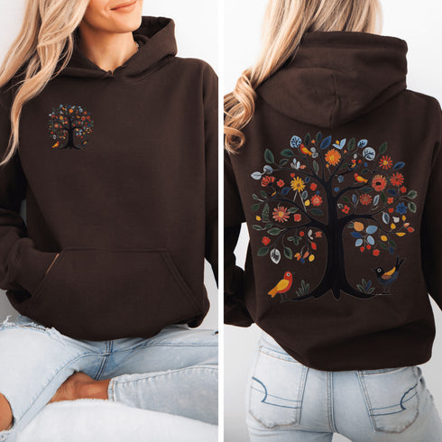 This hoodie features a delightful folk art design of vibrant birds perched in a tree adorned with colorful leaves and blooming flowers, creating a scene that radiates joy and creativity.