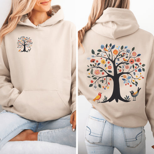 This hoodie features a delightful folk art design of vibrant birds perched in a tree adorned with colorful leaves and blooming flowers, creating a scene that radiates joy and creativity.
