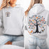 This hoodie features a delightful folk art design of vibrant birds perched in a tree adorned with colorful leaves and blooming flowers, creating a scene that radiates joy and creativity.
