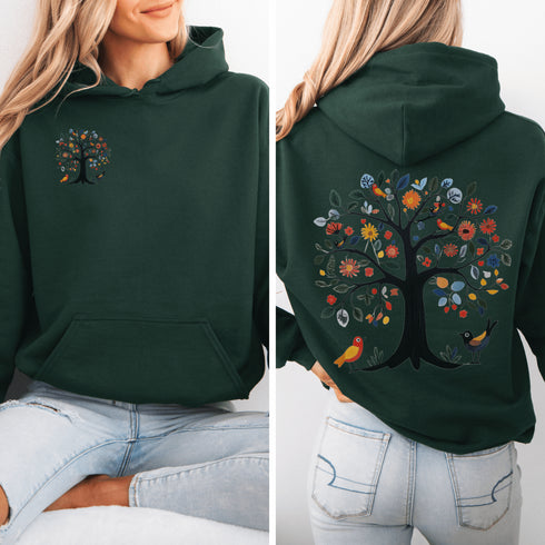 This hoodie features a delightful folk art design of vibrant birds perched in a tree adorned with colorful leaves and blooming flowers, creating a scene that radiates joy and creativity.