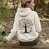 This hoodie features a delightful folk art design of vibrant birds perched in a tree adorned with colorful leaves and blooming flowers, creating a scene that radiates joy and creativity.
