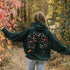 This hoodie features a delightful folk art design of vibrant birds perched in a tree adorned with colorful leaves and blooming flowers, creating a scene that radiates joy and creativity.