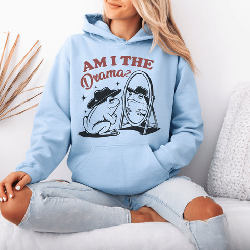 Yeehaw, drama lovers! Meet your new favorite hoodie: a fabulous frog in a cowboy hat, staring into a mirror and asking the ultimate question, "Am I the drama?"