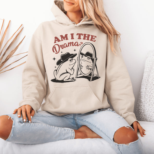 Yeehaw, drama lovers! Meet your new favorite hoodie: a fabulous frog in a cowboy hat, staring into a mirror and asking the ultimate question, "Am I the drama?"