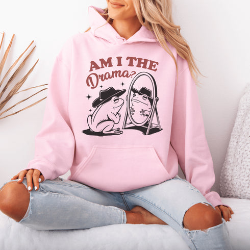 Yeehaw, drama lovers! Meet your new favorite hoodie: a fabulous frog in a cowboy hat, staring into a mirror and asking the ultimate question, "Am I the drama?"