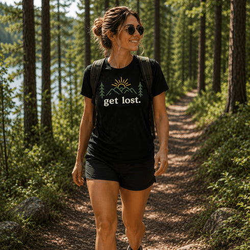 Woman hiking in a forest wearing a black t-shirt with 'get lost.' text.
