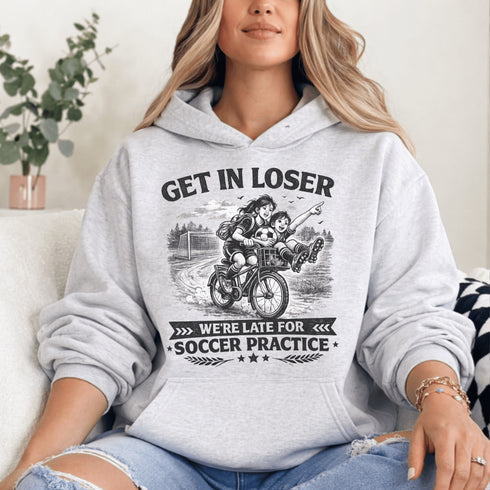 Funny soccer hoodie design showing two kids riding a bike to soccer practice with the phrase get in loser we’re late for soccer practice