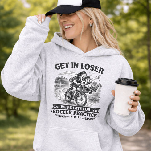 Funny soccer hoodie design showing two kids riding a bike to soccer practice with the phrase get in loser we’re late for soccer practice