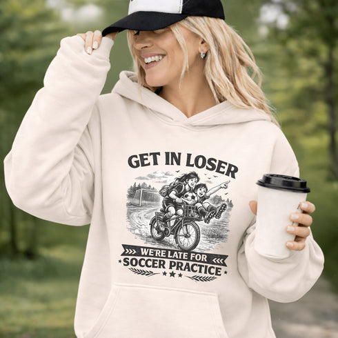 Funny soccer hoodie design showing two kids riding a bike to soccer practice with the phrase get in loser we’re late for soccer practice