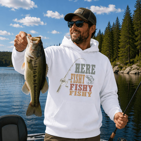 Person wearing a unisex hoodie with a vintage-inspired fishing graphic while holding a fish on a boat surrounded by a scenic lake and forest. Suitable for lifestyle, outdoor, fishing, cabin, camping, and product mockups.