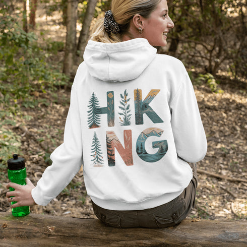 woman wearing hiking hoodie with large nature graphic on back sitting on log in forest