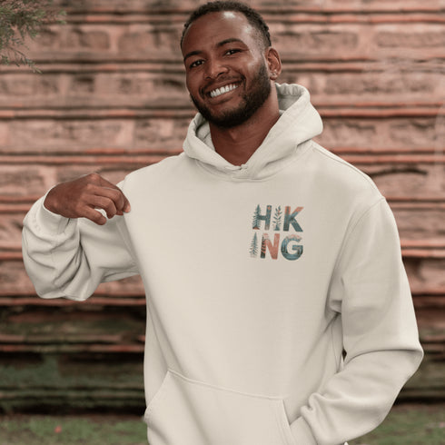 woman wearing hiking hoodie with large nature graphic on back sitting on log in forest