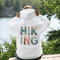 woman wearing hiking hoodie with large nature graphic on back sitting on log in forest