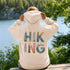 woman wearing hiking hoodie with large nature graphic on back sitting on log in forest