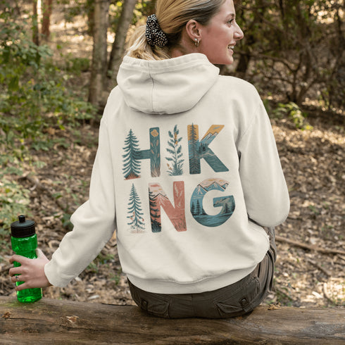 woman wearing hiking hoodie with large nature graphic on back sitting on log in forest
