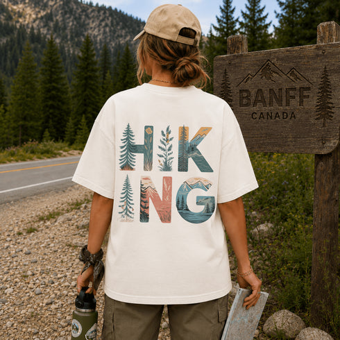 Person wearing a 'Hiking' t-shirt by a Banff, Canada sign.