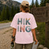 Person wearing a pink t-shirt with 'Hiking' design, standing near a Banff Canada sign.