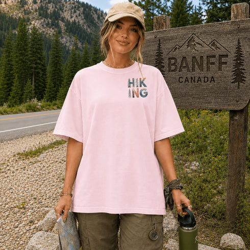 Woman in a pink t-shirt with 'Hiking' design standing next to a Banff Canada sign.