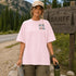 Woman in a pink t-shirt with 'Hiking' design standing next to a Banff Canada sign.