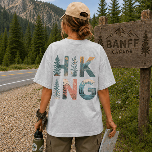 Person wearing a 'Hiking' t-shirt by a Banff, Canada sign.