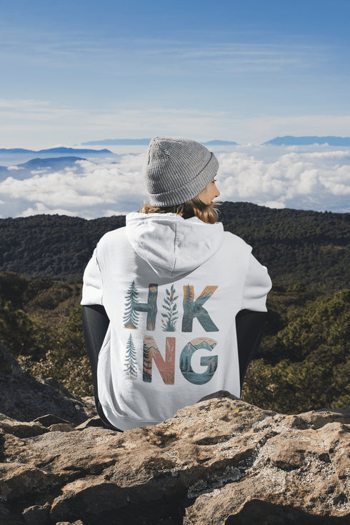 woman wearing hiking hoodie with large nature graphic on back sitting on a mountain
