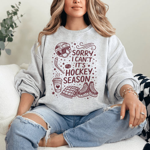 Funny hockey season sweatshirt with “Sorry I Can’t It’s Hockey Season” design featuring skates, stick, puck, and coffee cup – cozy rink apparel for hockey moms and fans
