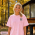 Home Is Out Here Comfort Colors 1717 graphic t-shirt featuring mountain, pine trees, and wilderness artwork with a small left chest logo and large back print.