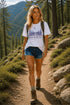 Woman hiking on a trail with mountains and trees in the background