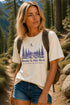 Woman wearing a t-shirt with a nature-themed design in a forest setting