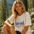 Woman wearing a t-shirt with a nature-themed design in a forest setting